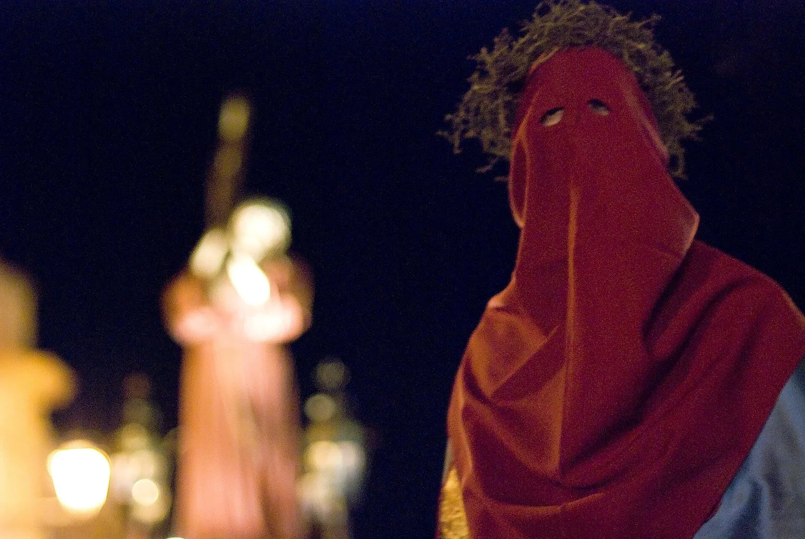 Processione notturna della Settimana Santa in un centro storico salentino con confratelli e statue portate a spalla